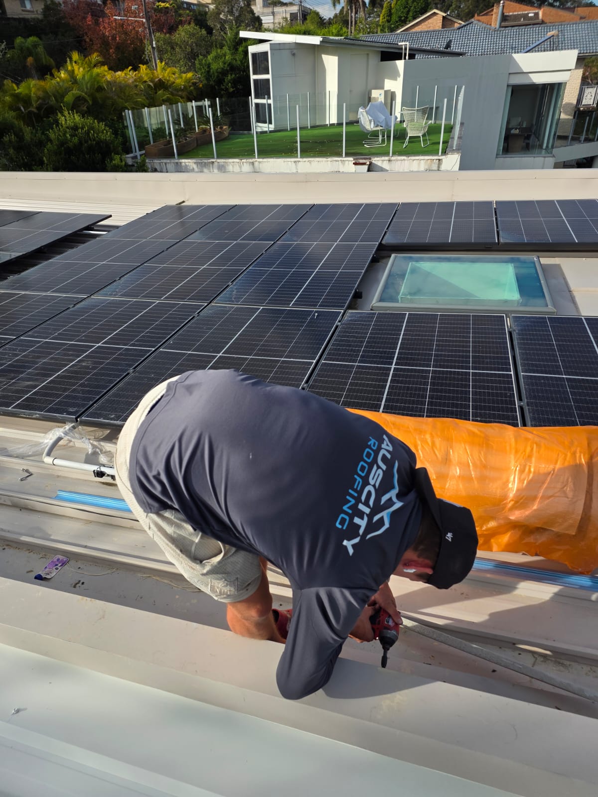 Roofer working beside solar panels and a skylight